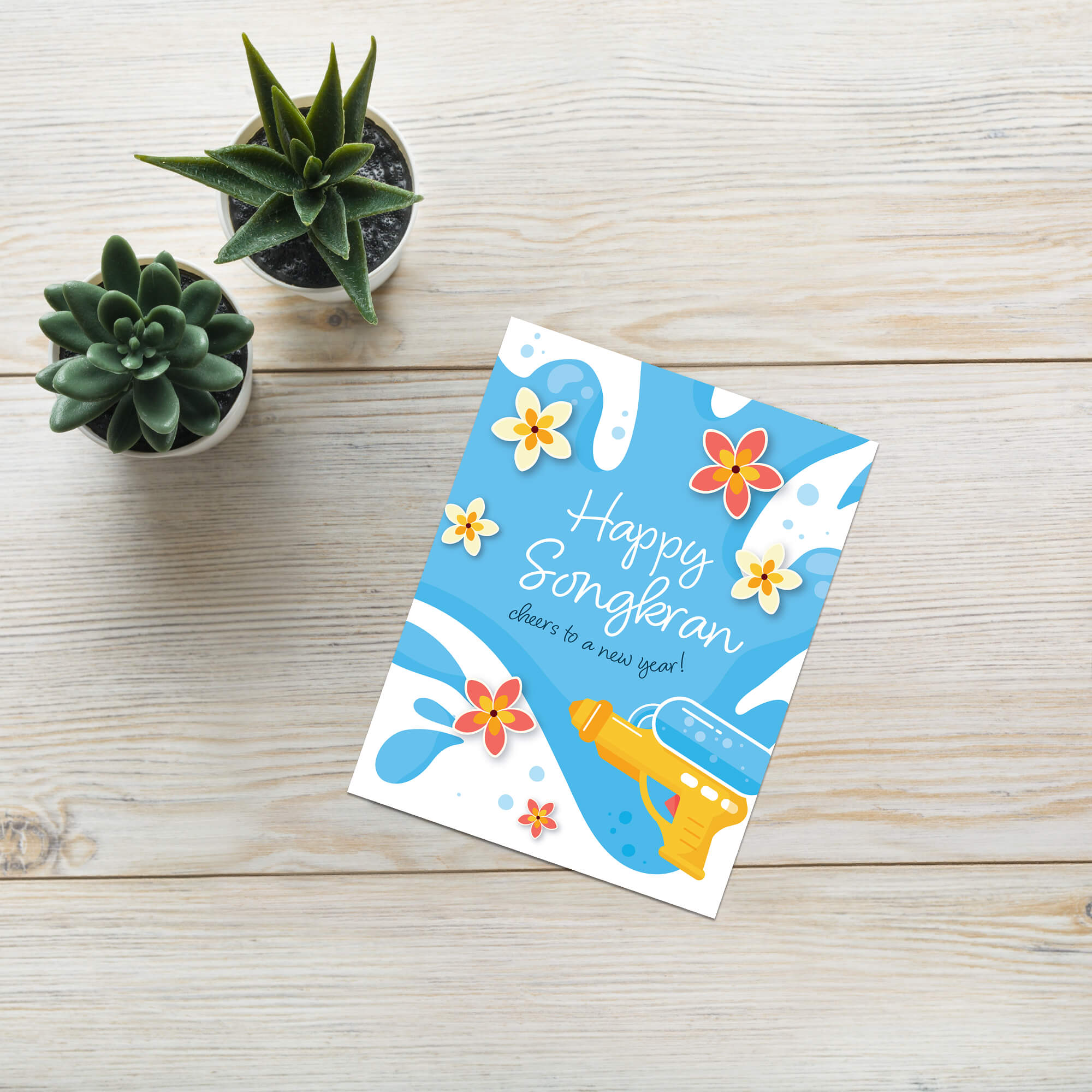 Greeting card with 'Happy Songkran' for Thai New Year with flowers and a water soaking squirt gun on a blue background.