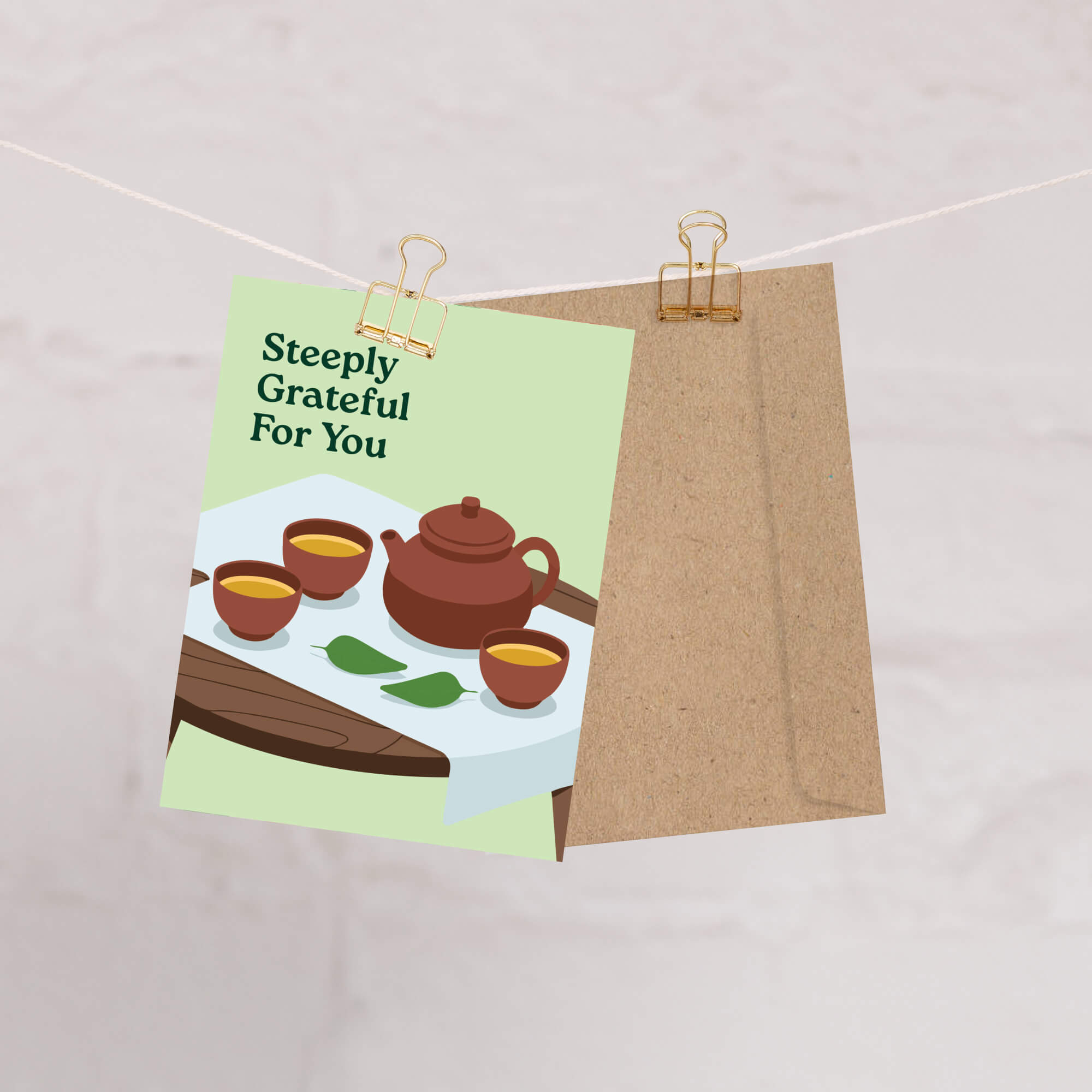 Greeting card with tea illustration and 'Steeply Grateful For You' text, attached to a string with a paper clip.