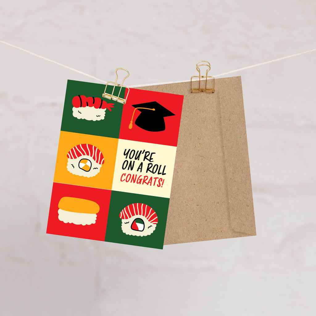 graduation card with sushi illustrations and a graduation cap, featuring the text 'You're on a roll congrats!'