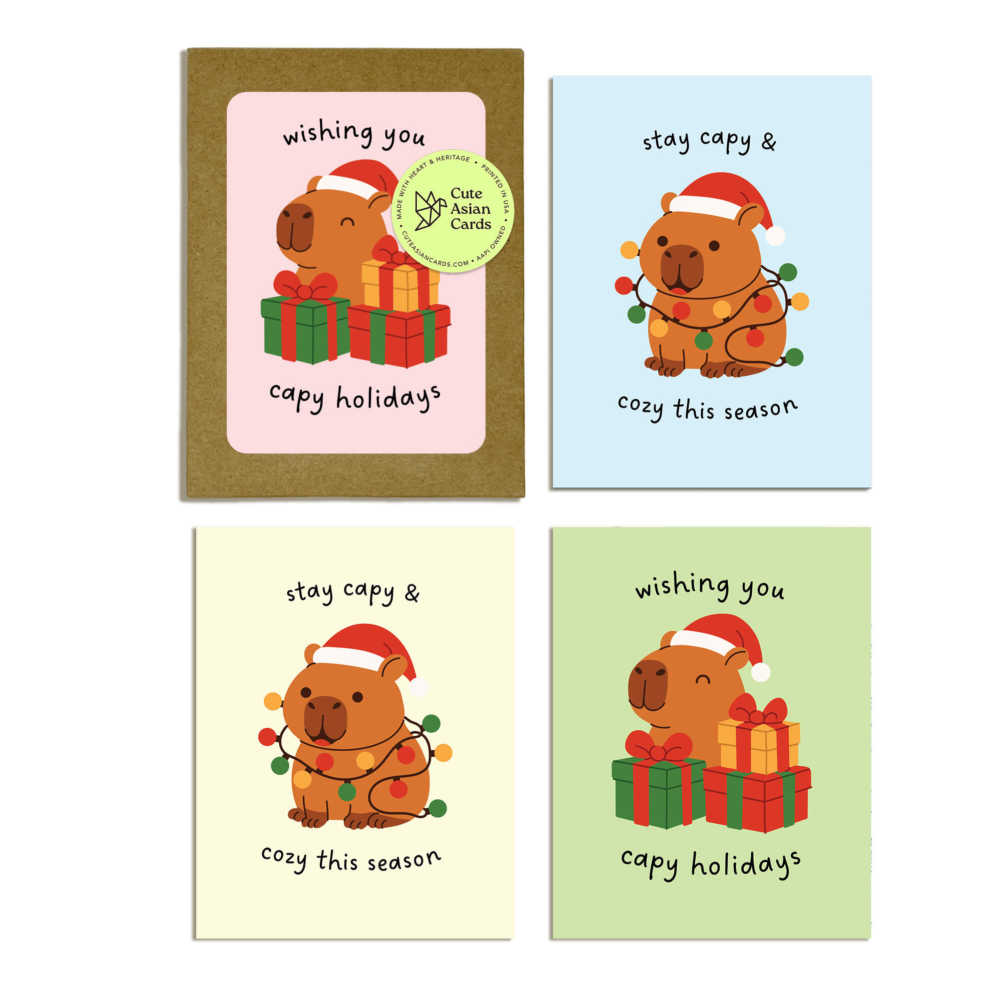 Colorful Capy Holidays card pack showing 4 holiday designs with capybaras in Santa hats, wrapped in string lights or sitting with gift boxes. Each design appears twice for a total of 8 cards with kraft envelopes.