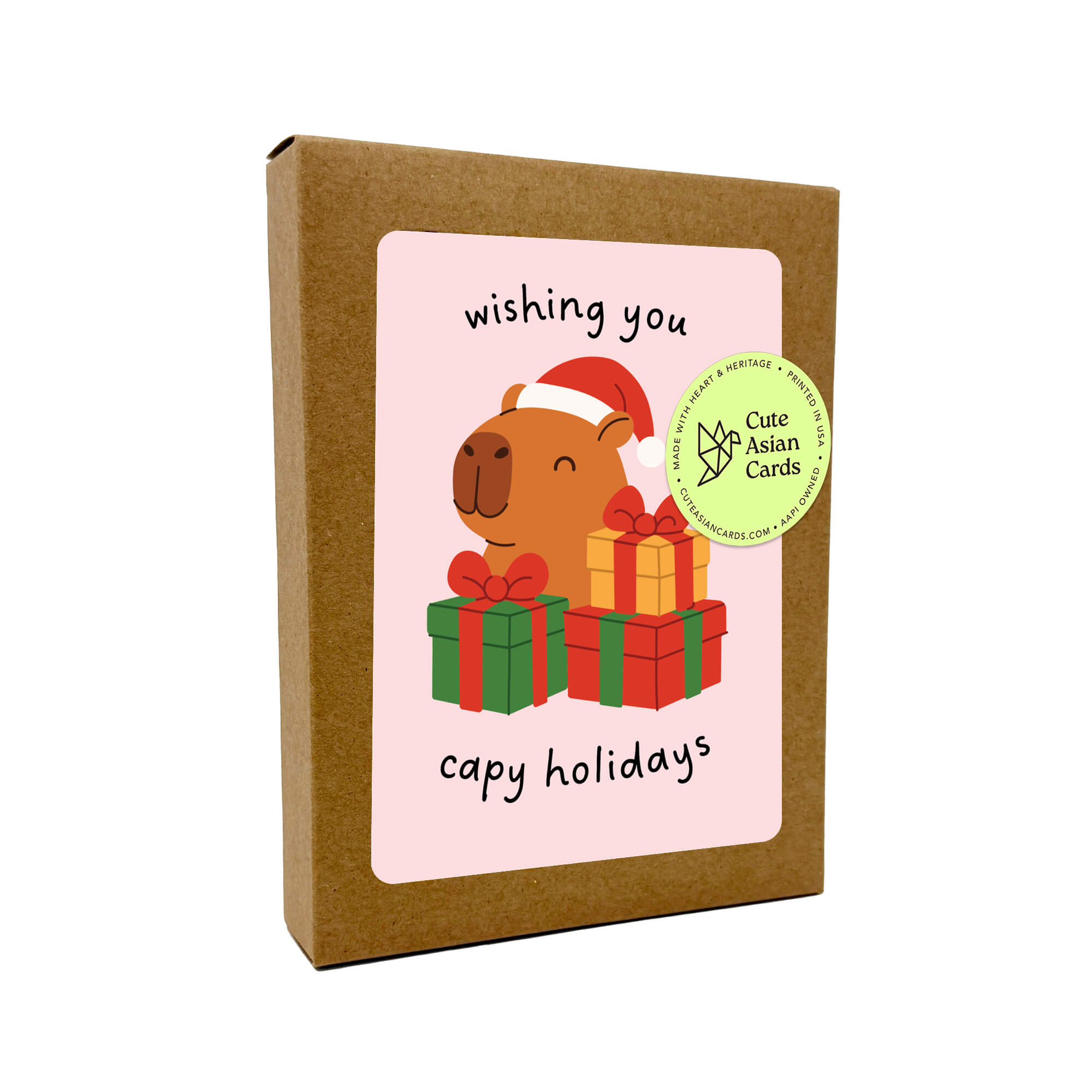 Colorful Capy Holidays card pack showing 4 holiday designs with capybaras in Santa hats, wrapped in string lights or sitting with gift boxes. Each design appears twice for a total of 8 cards with kraft envelopes.