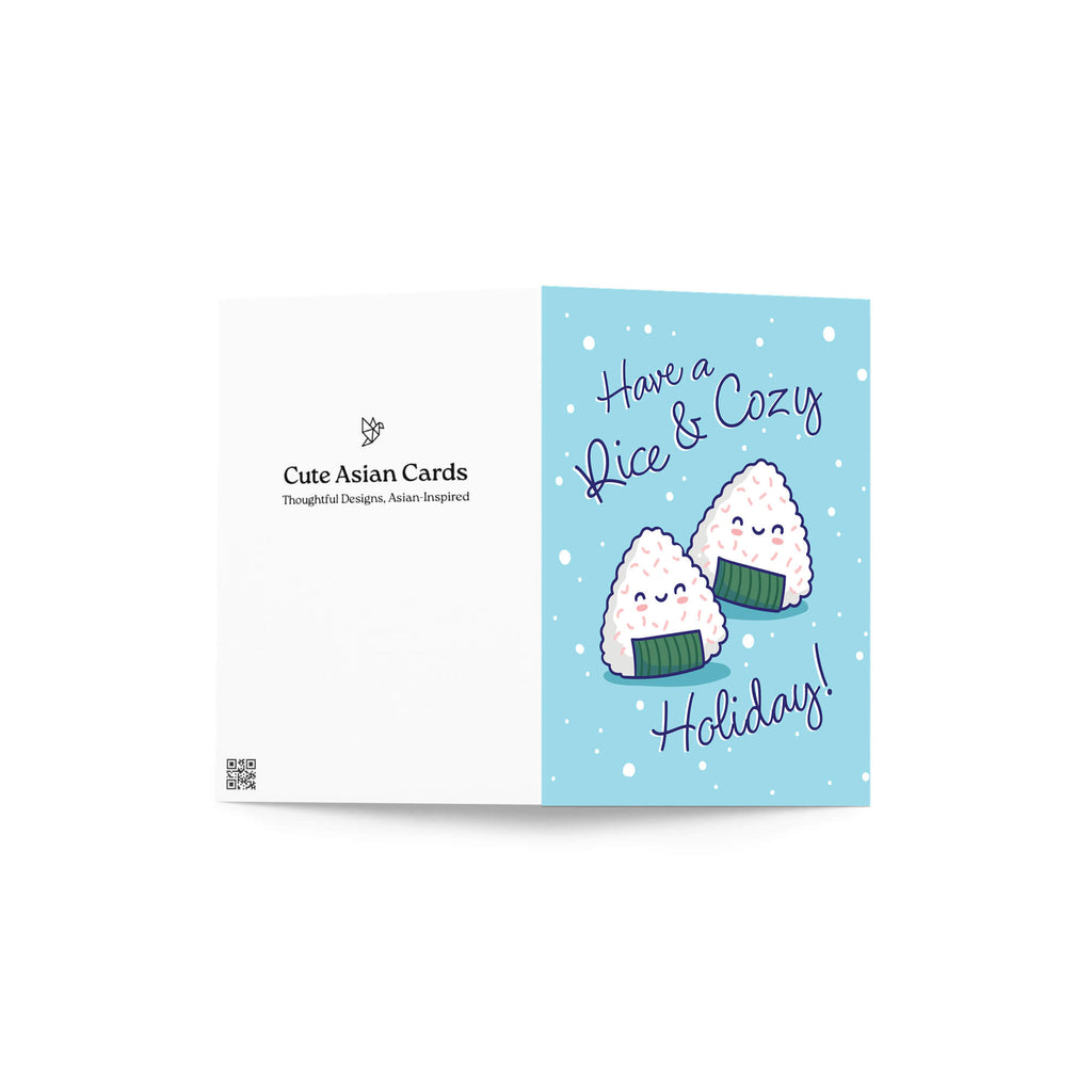 unique christmas card with Two smiling onigiri (japanese rice ball snacks) on snowy blue with text “Have a Rice & Cozy Holiday.”