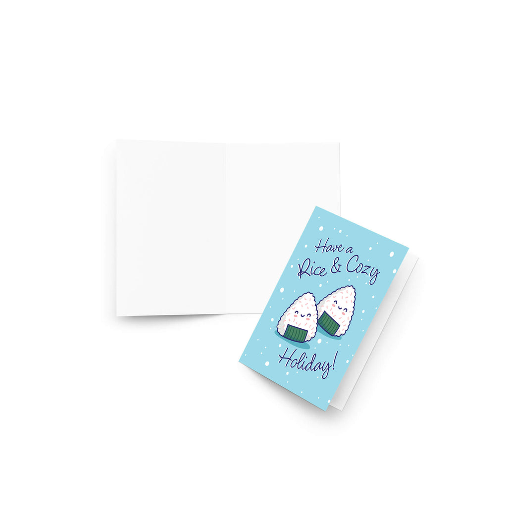 unique christmas card with Two smiling onigiri (japanese rice ball snacks) on snowy blue with text “Have a Rice & Cozy Holiday.”