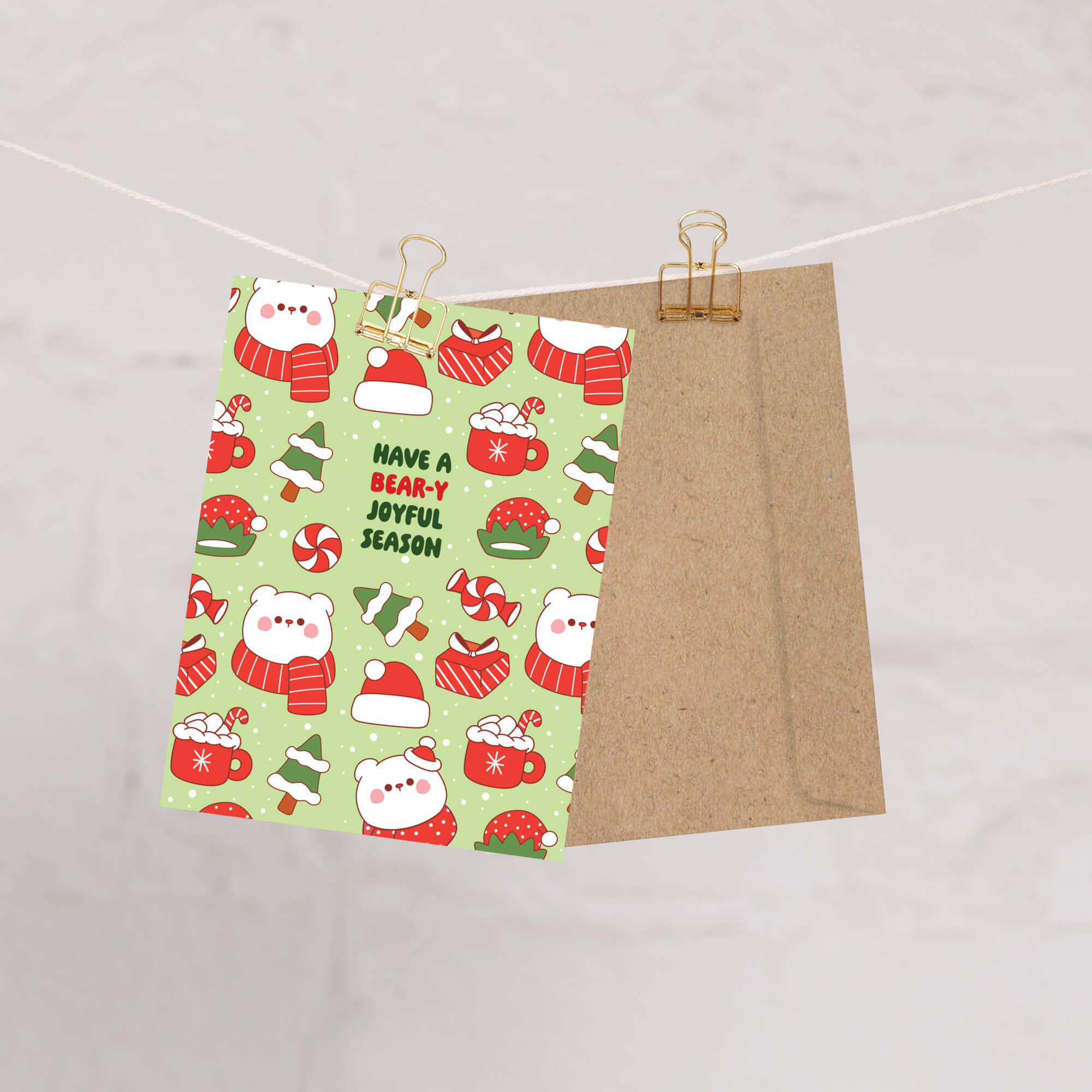 unique Christmas card with white polar bear in red scarf and santa hat and holiday elements on a green background with text "have a bear-y joyful season"