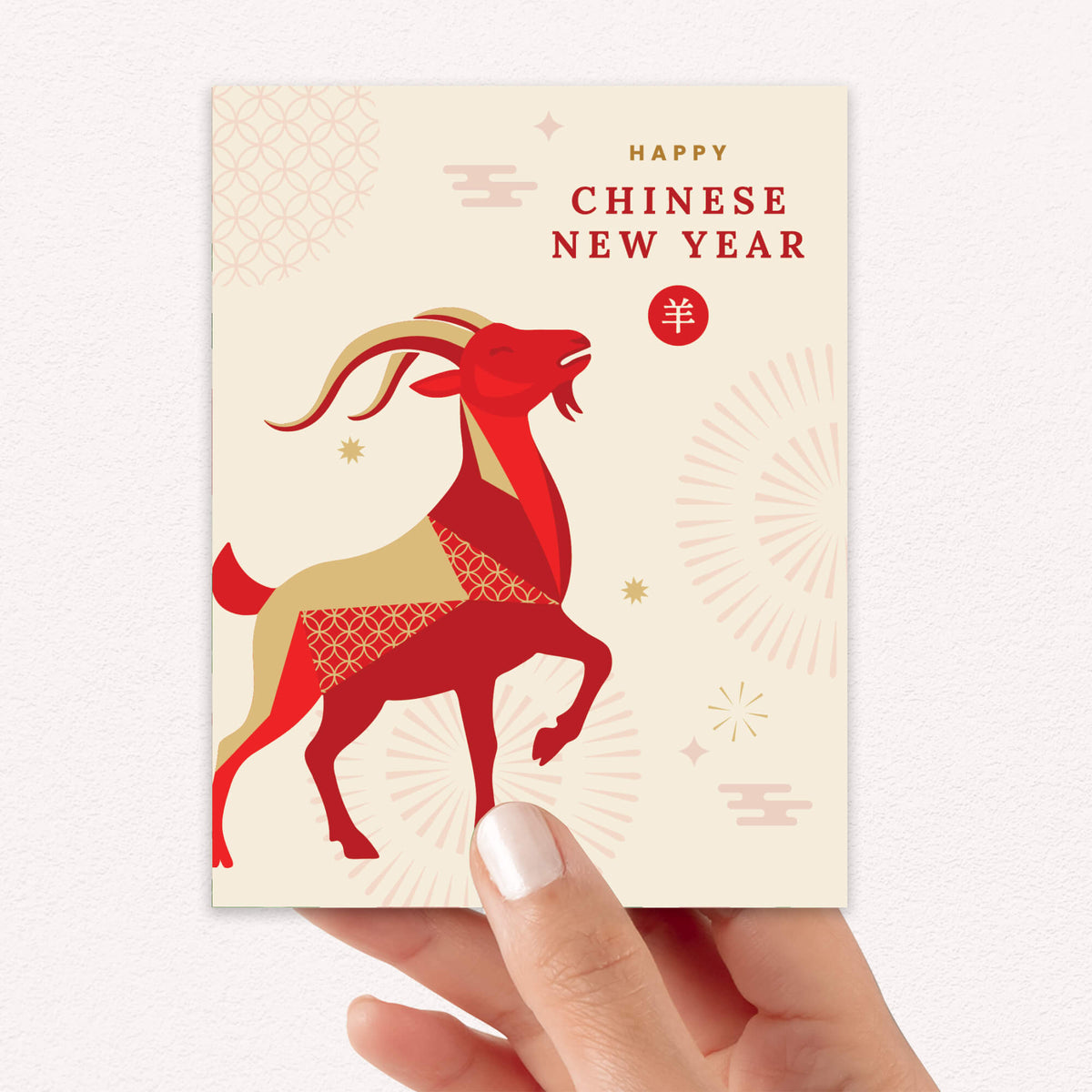 A hand holding a Chinese New Year greeting card featuring a stylized red and gold goat illustration with the text 'Happy Chinese New Year' on a cream background.