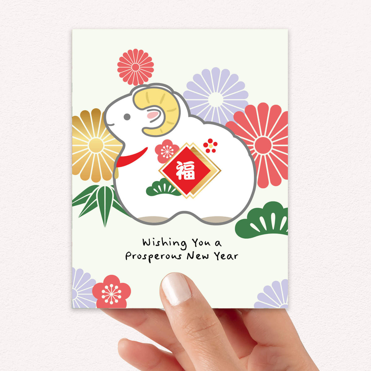 A hand holds a Chinese New Year greeting card 2027 featuring the Year of the Goat illustration with a red Chinese-style福 emblem, colorful flowers, and the text 'Wishing You a Prosperous New Year' on a light background.