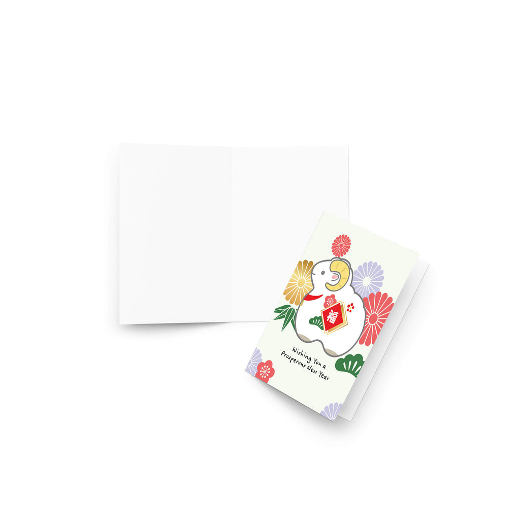A folded chinese new year card with a colorful illustration of the year of the sheep and the text 'Wishing You a prosperous New Year' is shown next to an open blank white envelope on a clean white background.